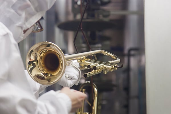 Operaio che pulisce uno strumento musicale durante il processo di lavaggio in una fabbrica Yamaha.