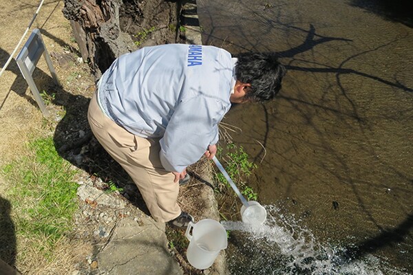 Membro dello staff Yamaha che conduce un’ispezione sulla qualità dell’acqua presso un fiume.