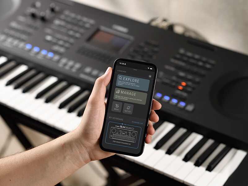 PSR-SX920 e una mano che tiene uno smartphone con lo schermo di un lettore musicale.