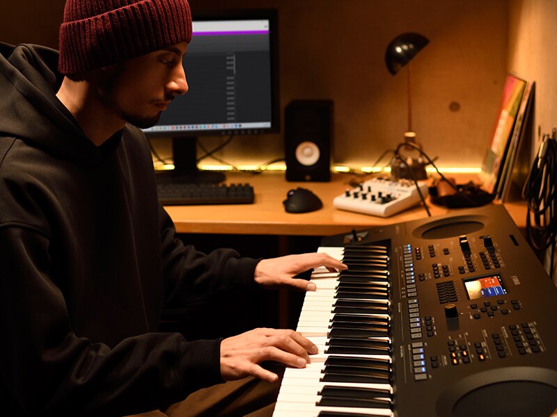 Persona che suona una tastiera PSR-SX620 in un home studio.