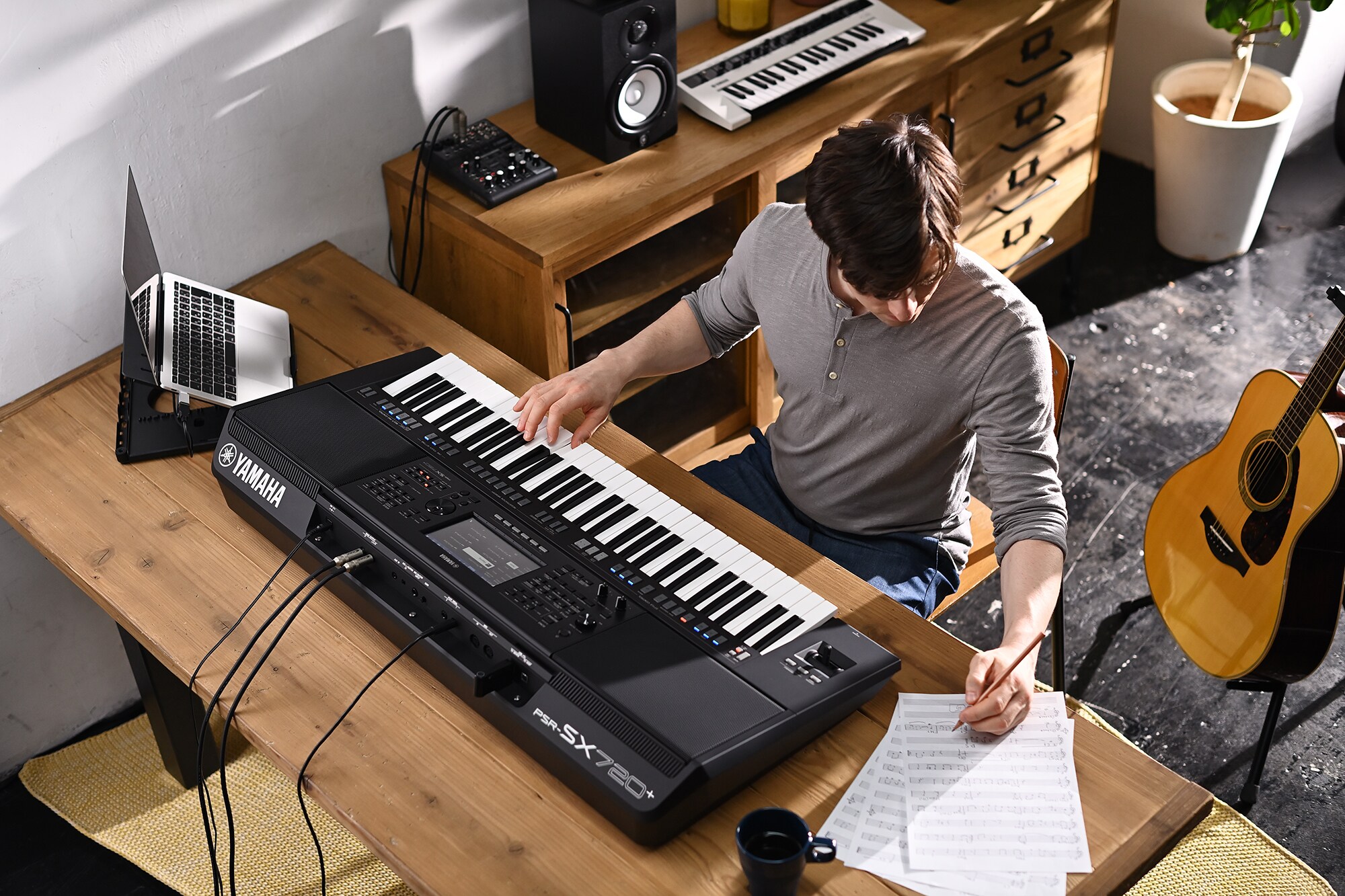 Foto di una persona che scrive su uno spartito mentre suona la Yamaha Workstation Arranger PSR-SX720+