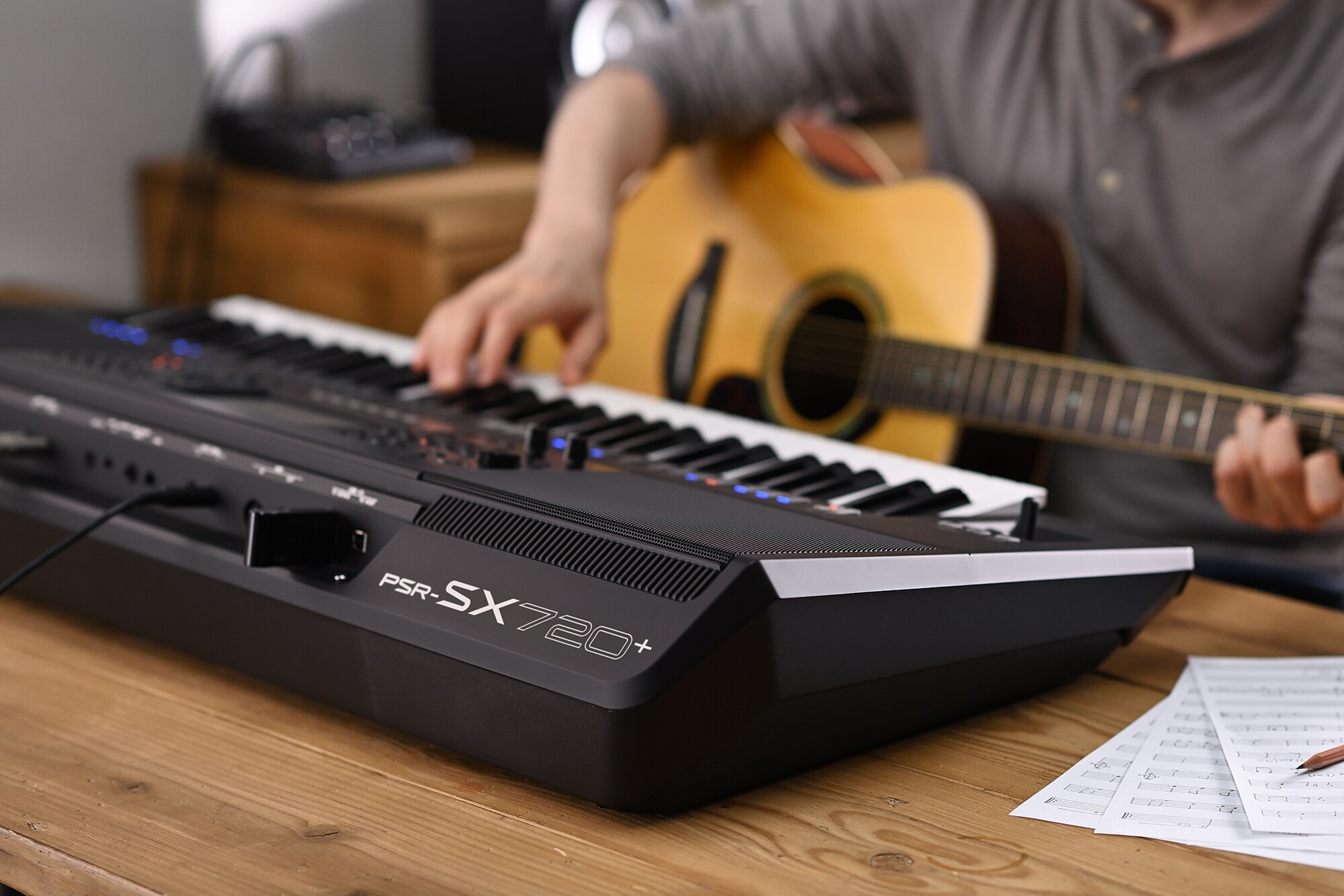 Foto di una persona che suona la Yamaha Workstation Arranger PSR-SX720+ tenendo in mano una chitarra