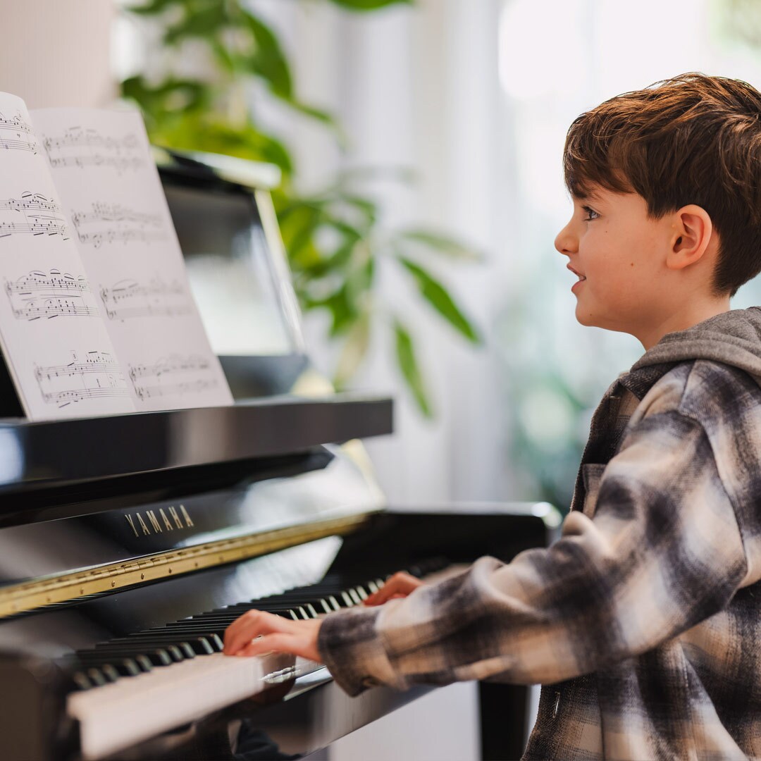 Un bambino si diverte a suonare il pianoforte verticale della Serie B