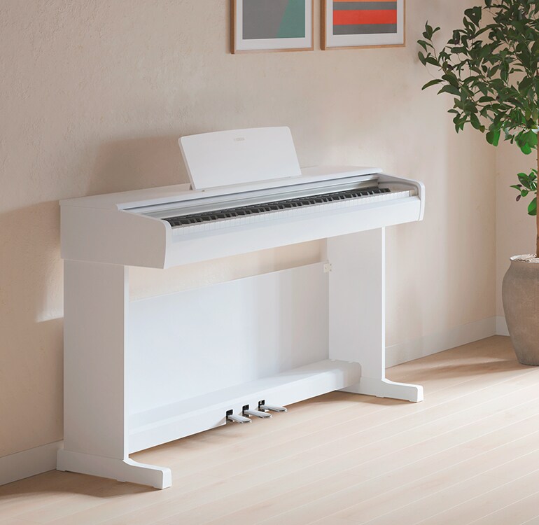 Un soggiorno con un pianoforte ARIUS bianco, piante da appartamento e un divano, armoniosamente integrati con l’arredamento
