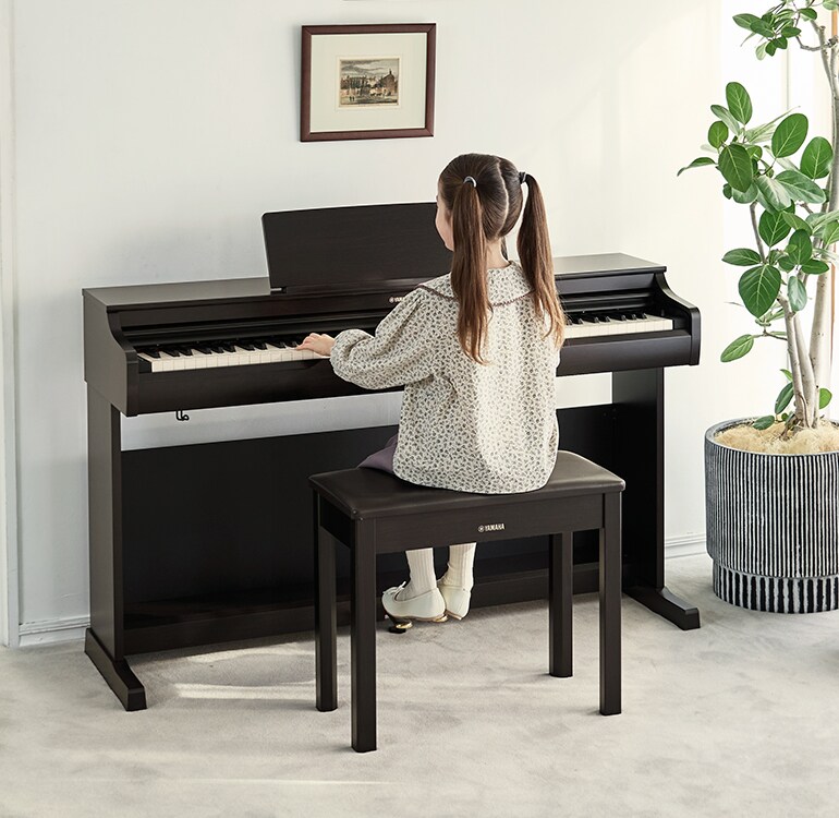 Una ragazza che si esercita su un pianoforte ARIUS in un soggiorno