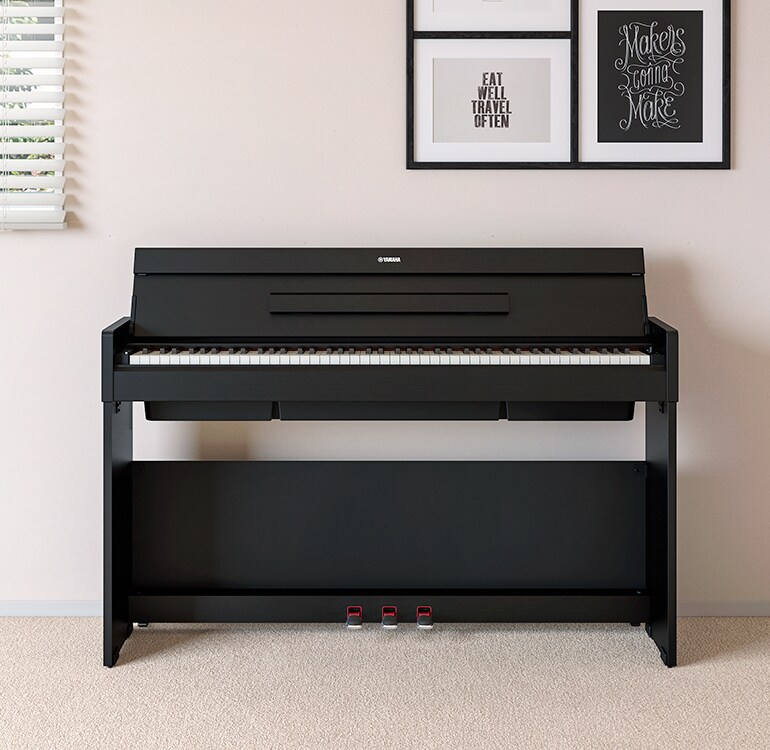 Un soggiorno con un pianoforte ARIUS nero posizionato accanto a mensole a muro su cui si trovano lampade e un diffusore, armoniosamente integrato con l’arredamento.