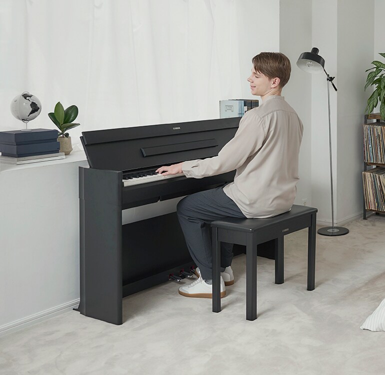 Un uomo che suona un pianoforte ARIUS in una camera da letto in un ambiente rilassato
