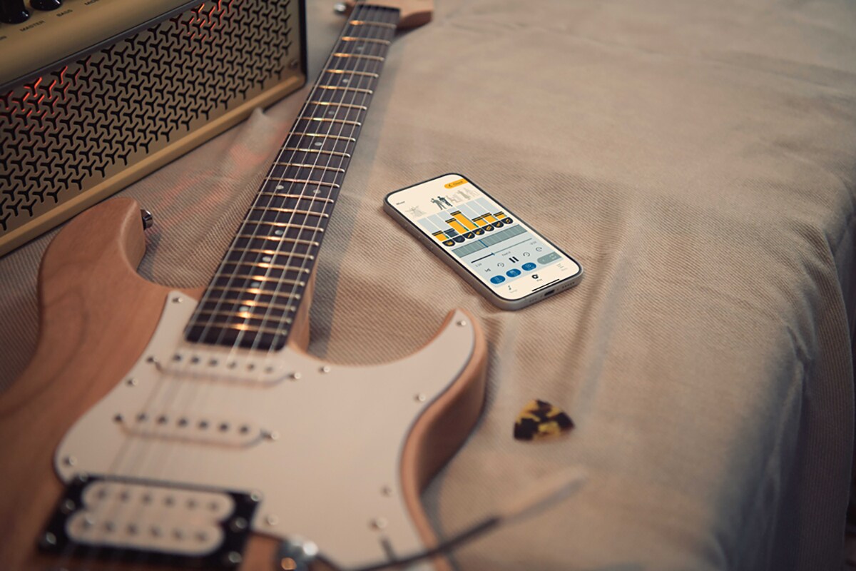 L'app di esercitazione musicale Extrack vicino a una chitarra elettrica e a un amplificatore