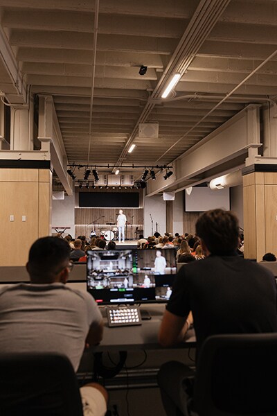 Church volunteers participating in audio system training beside equipment racks and production systems.